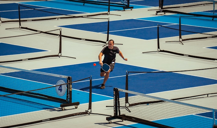 A man plays pickleball on an outdoor court.