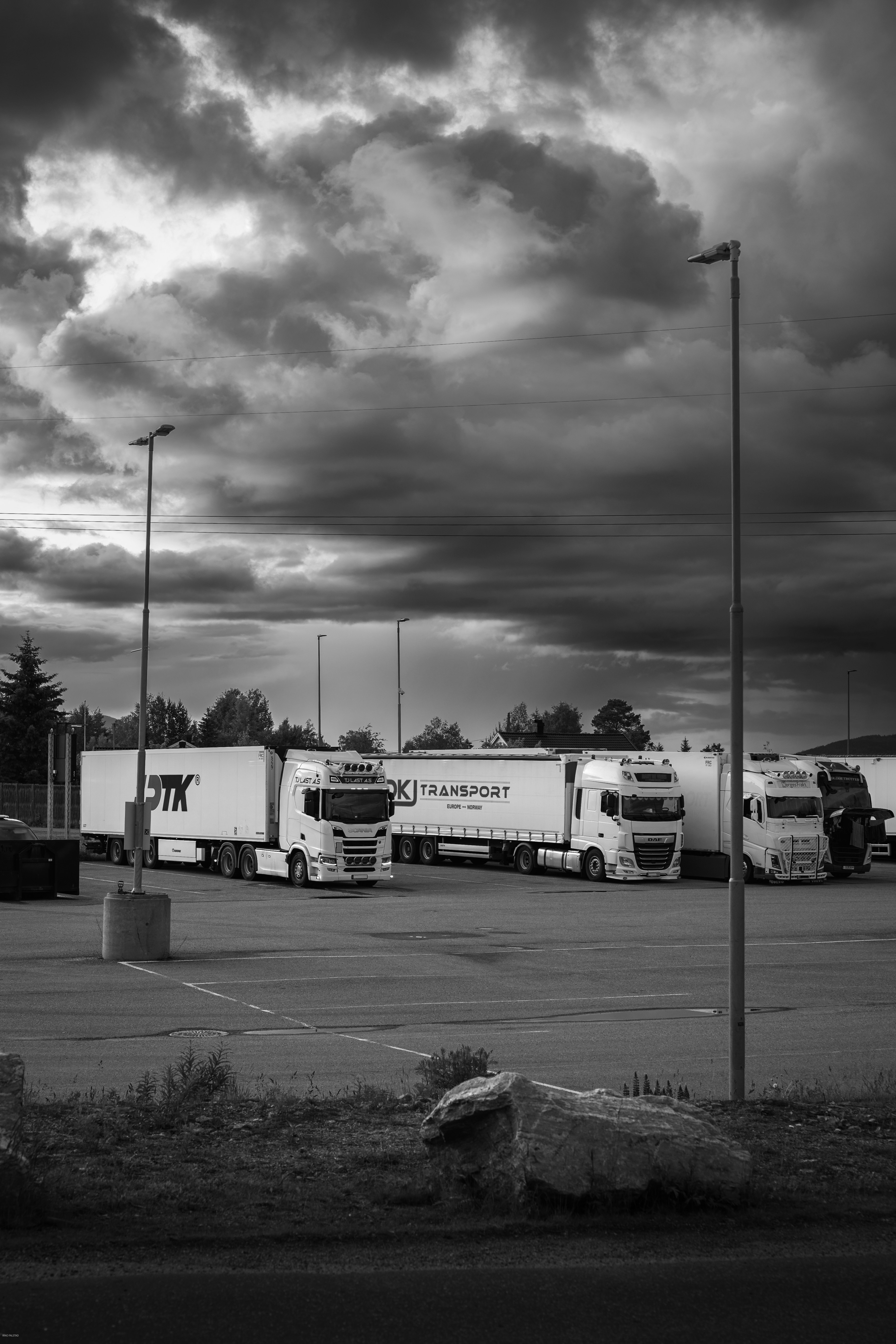 Trucks are parked under a cloudy sky.