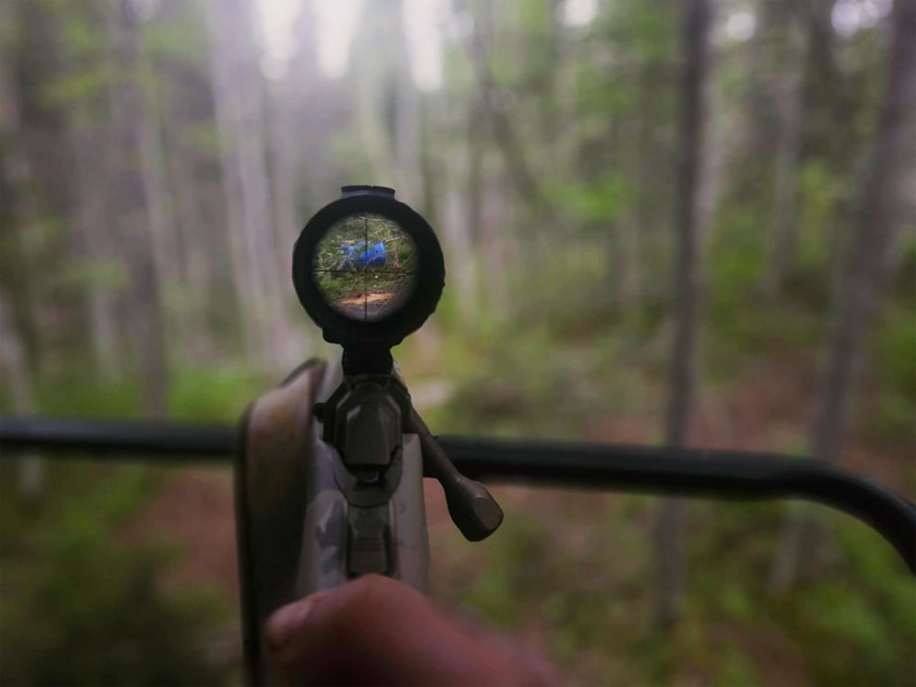 Hunter at a rifle range zeroing a scoped hunting rifle on sandbags before the season
