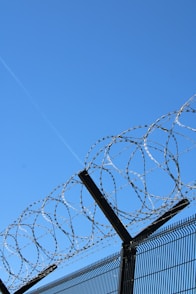 Barbed wire fence against a blue sky.