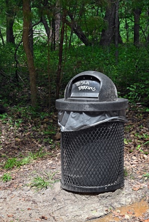 Trash can in a forest that reads "tesla parking."
