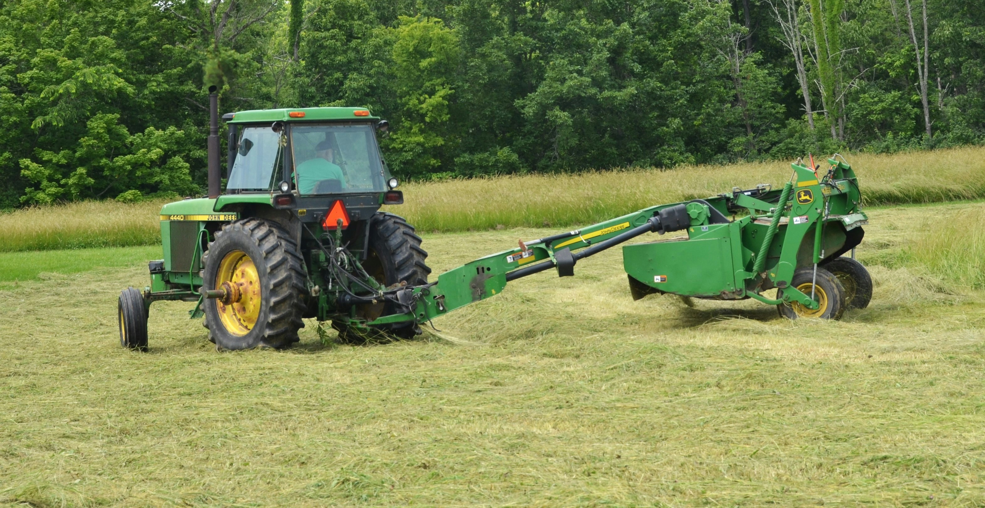 John Deere Tractor and mower/conditioner cutting Hay
