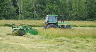 A tractor cuts hay in a field.
