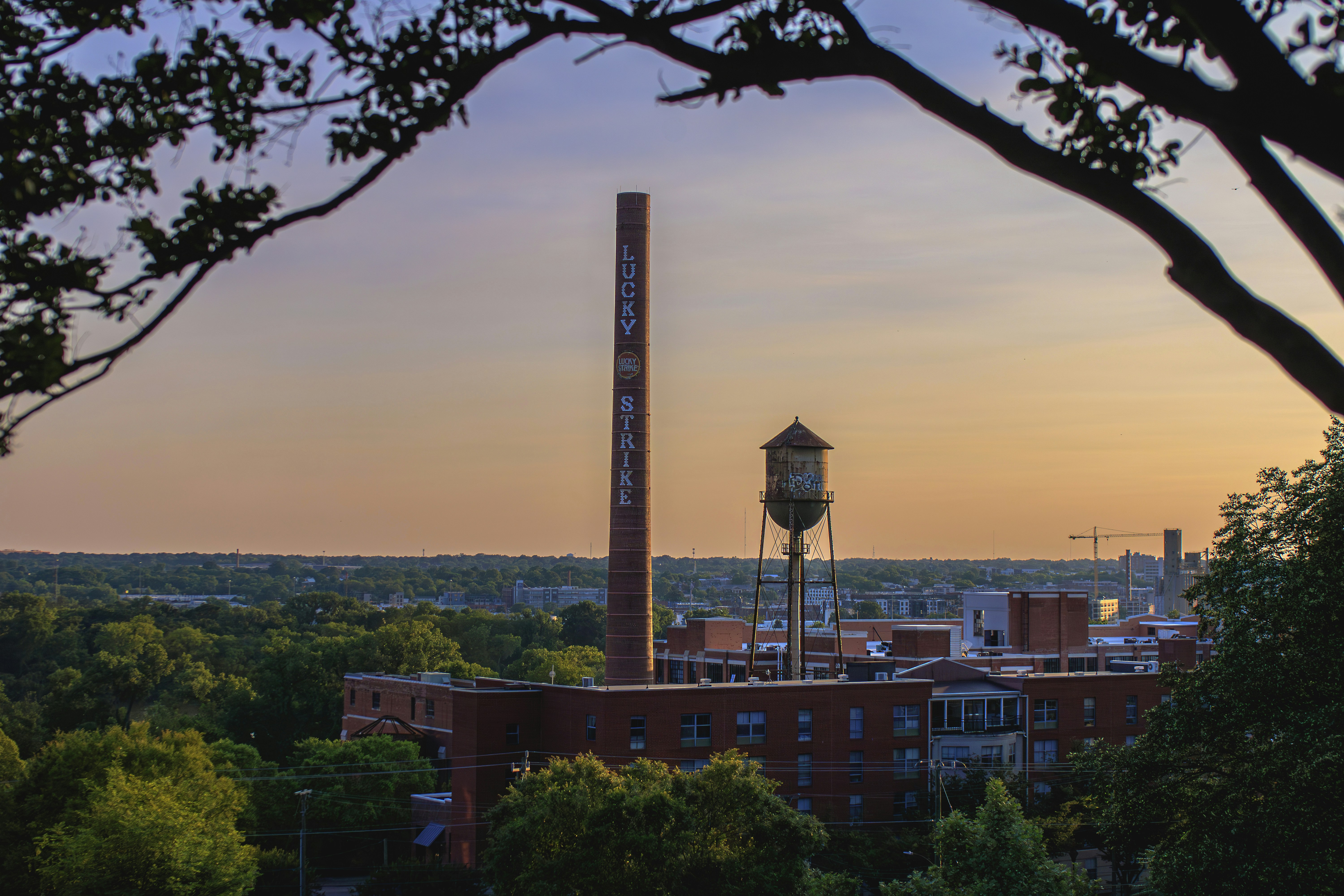 A factory and water tower stand against the sunset.