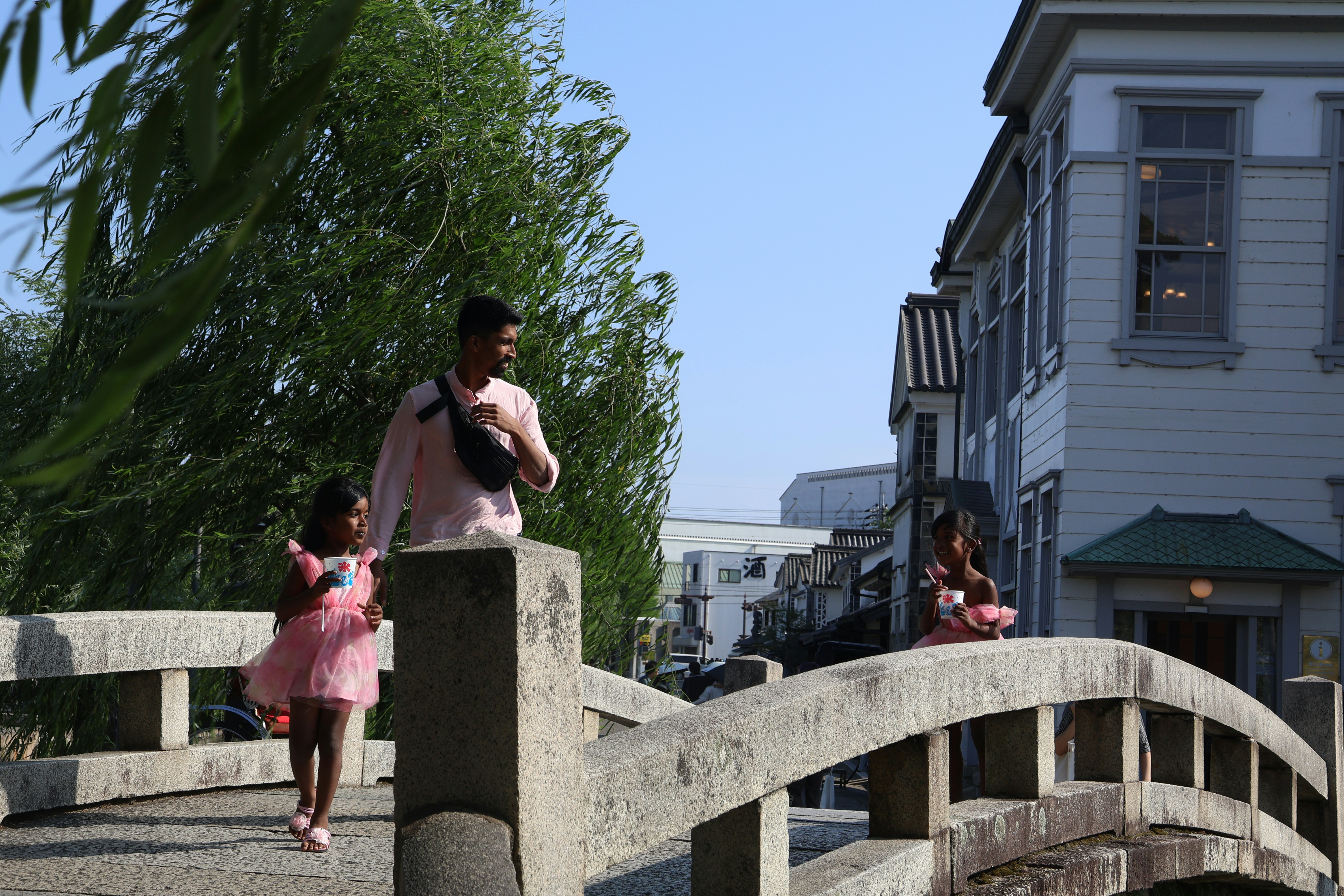 People walk on a bridge in front of a building.