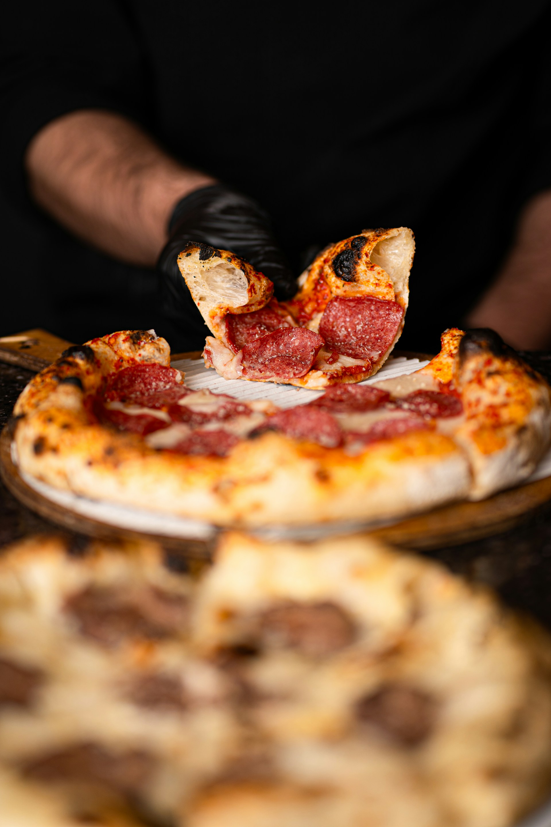 Someone is taking a slice of pepperoni pizza.