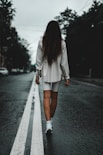 A woman walks alone down a road.