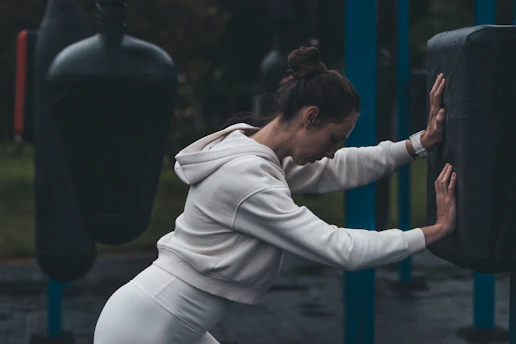 A woman stretches at an outdoor boxing gym.