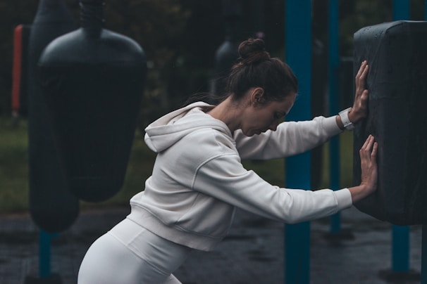 A woman stretches at an outdoor boxing gym.