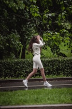 Woman jogs along a wet pathway near green trees.