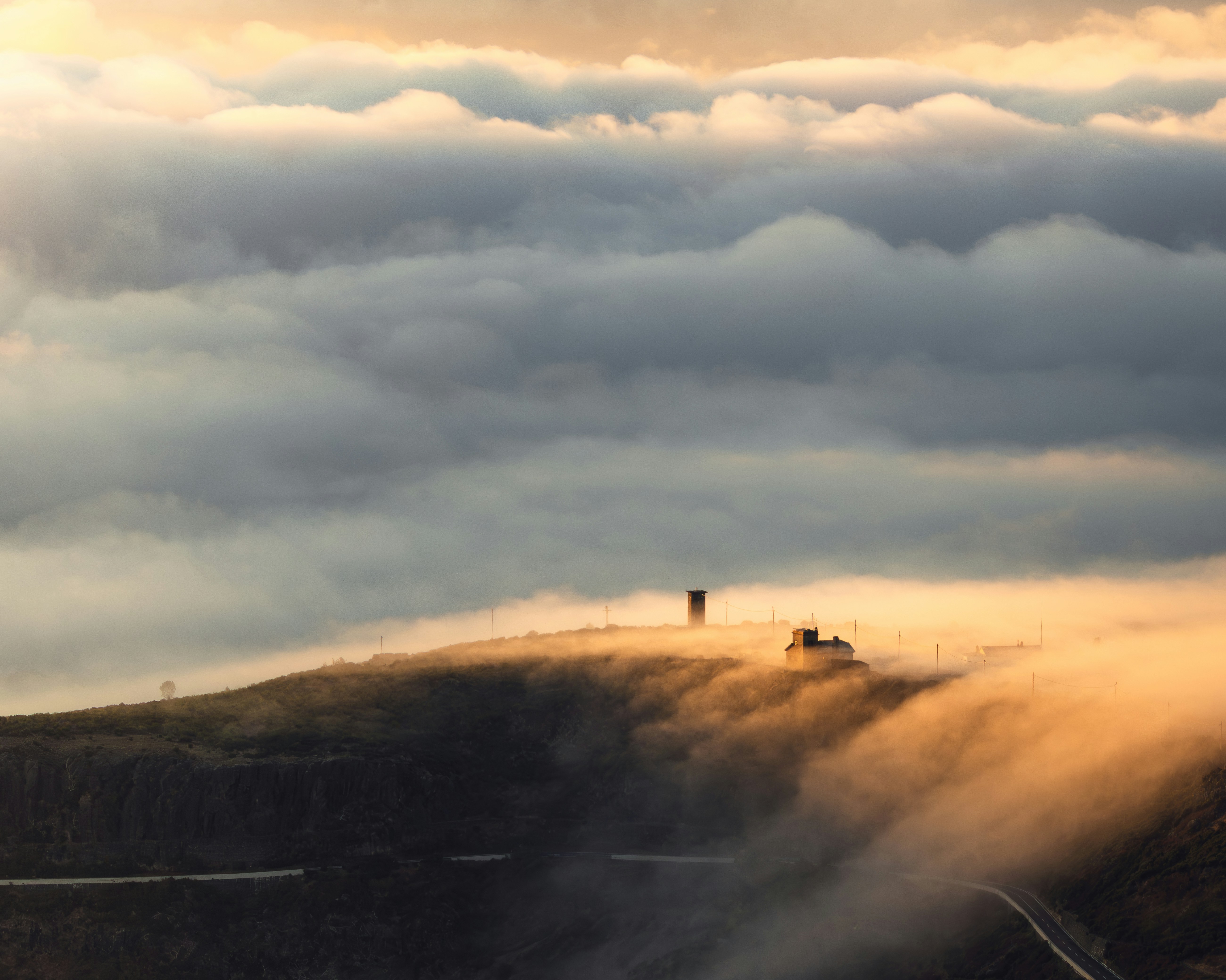 Clouds surround a mountain peak with structures
