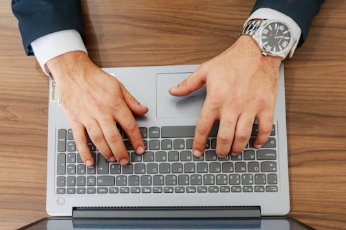 A person types on a laptop at a desk.