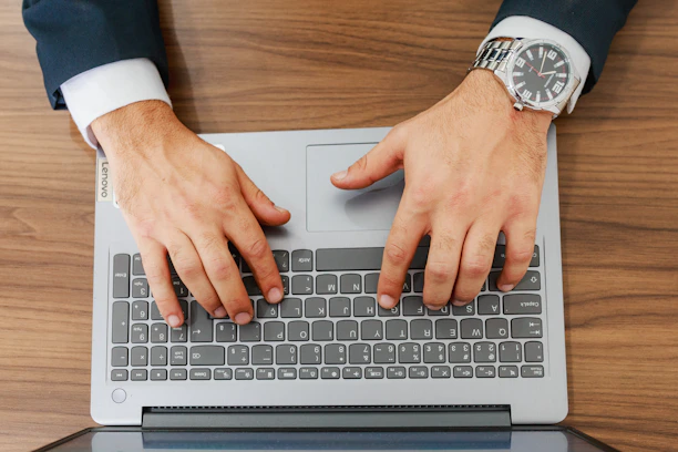 A person types on a laptop at a desk.