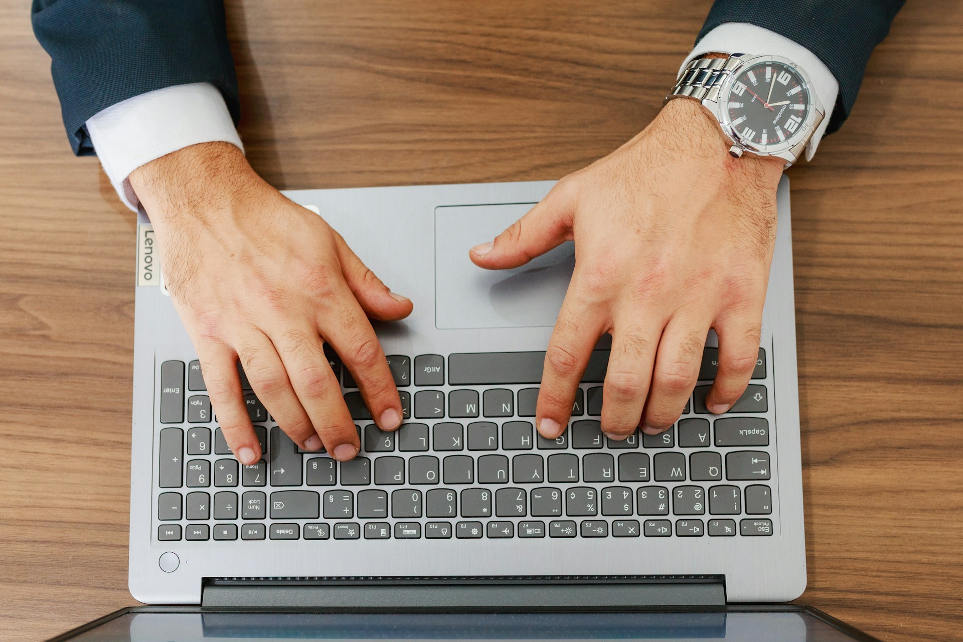 A person types on a laptop at a desk.