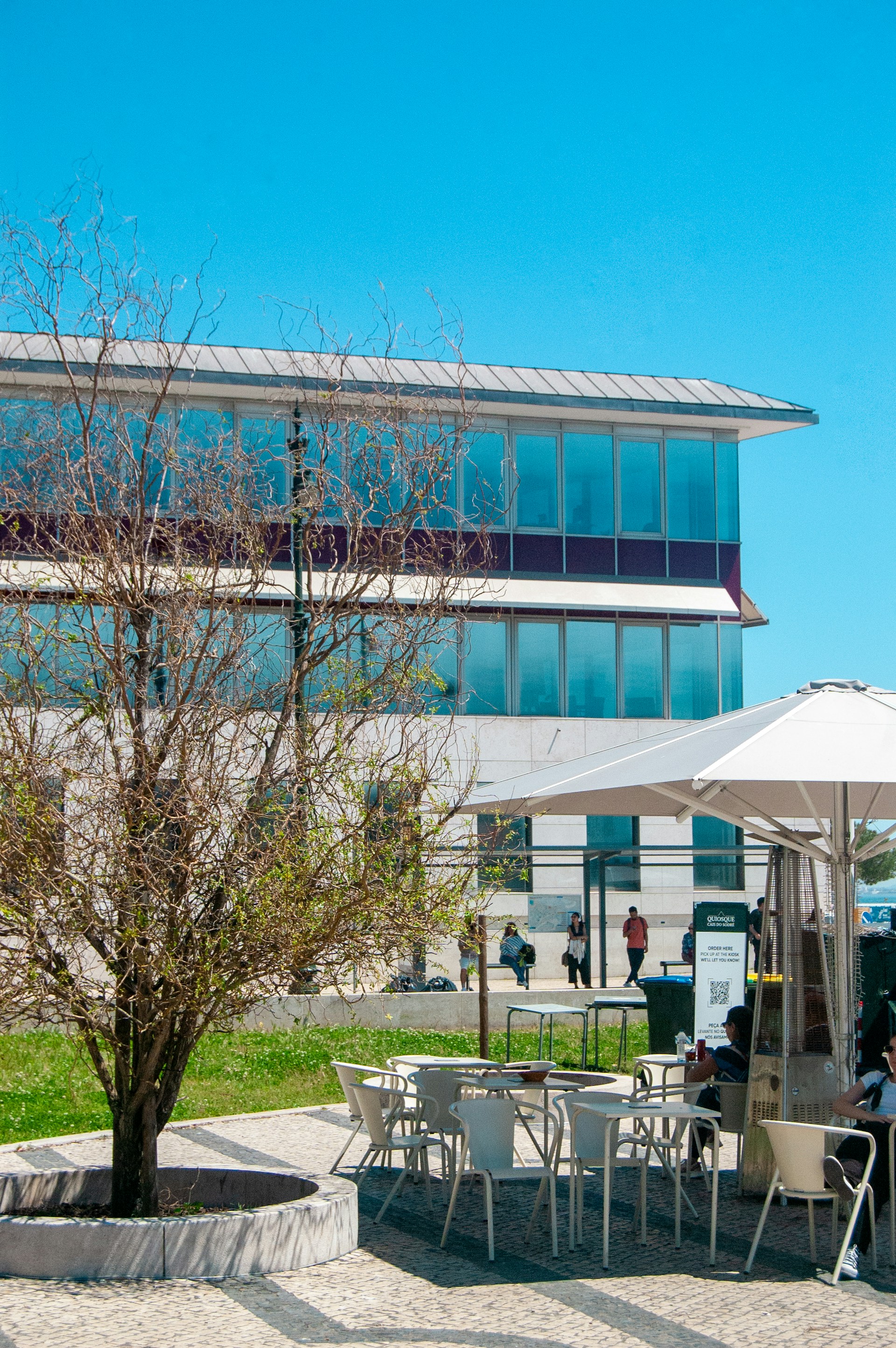 A sunny outdoor cafe next to a modern building.