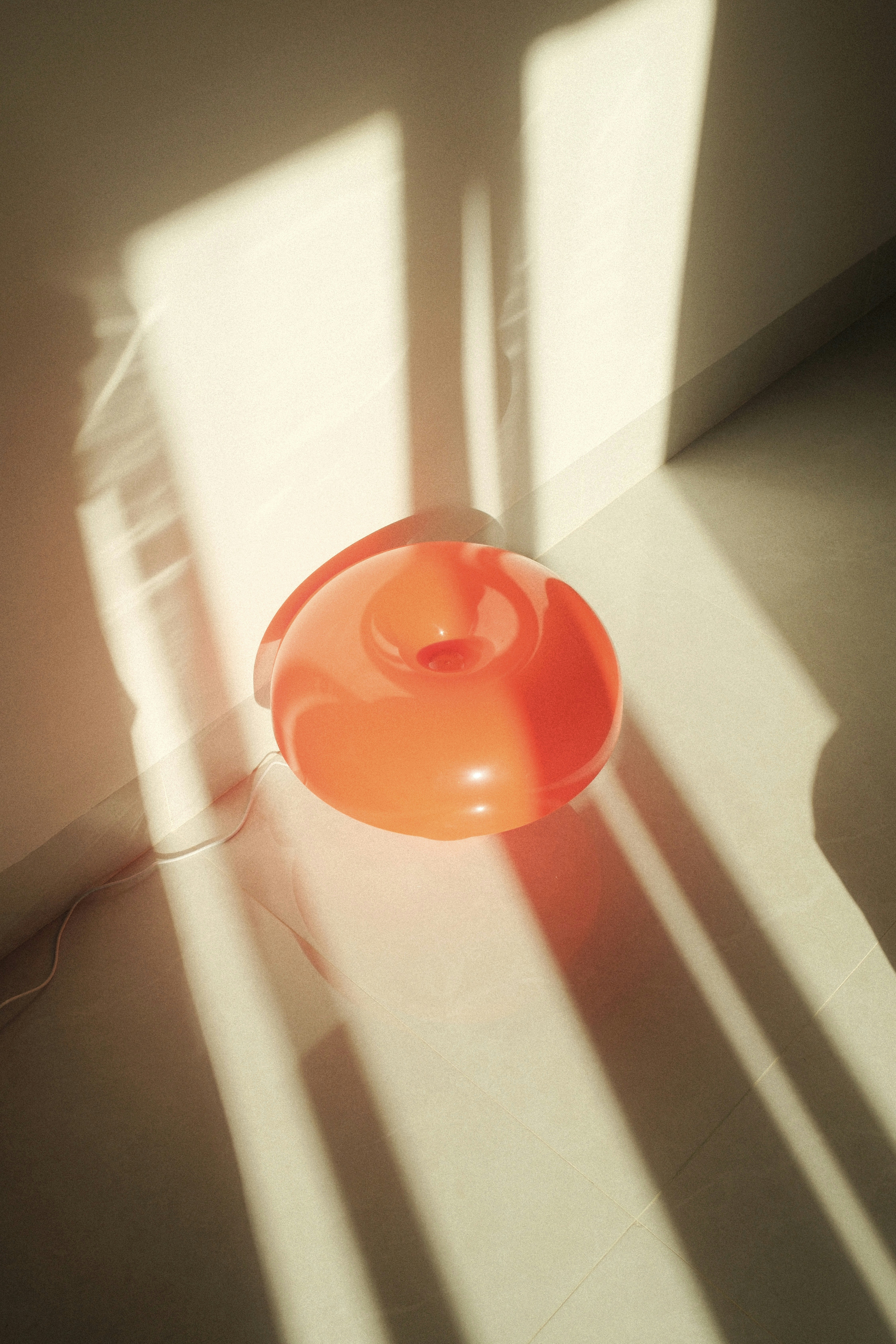 Orange object sits in sunlight on the floor.