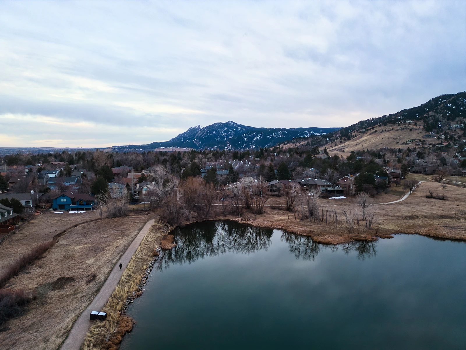A calm lake with Boulder, Colorado and the foothills in the distance under a cloudy sky