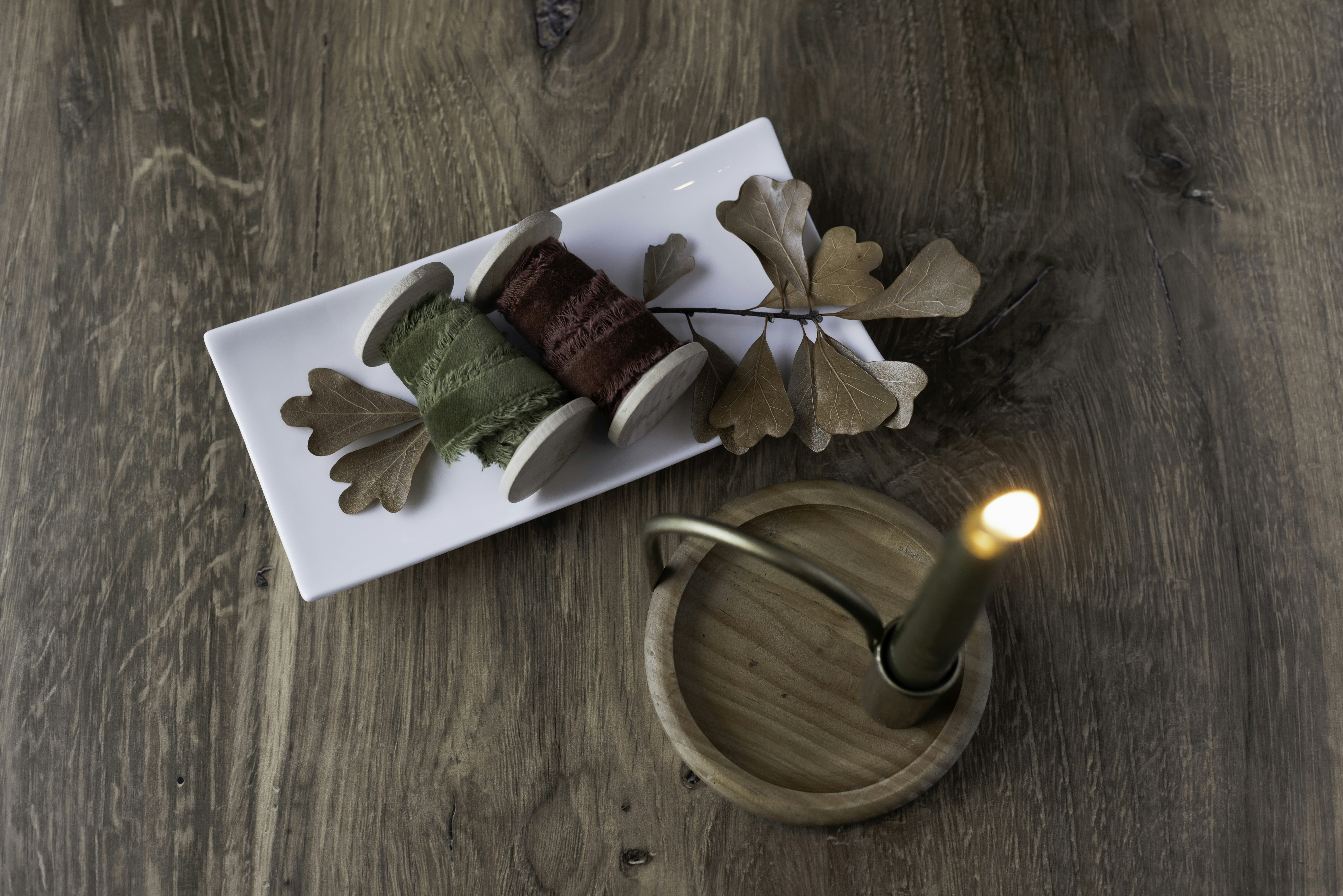 Vela, carretéis e decorações de madeira em uma mesa.