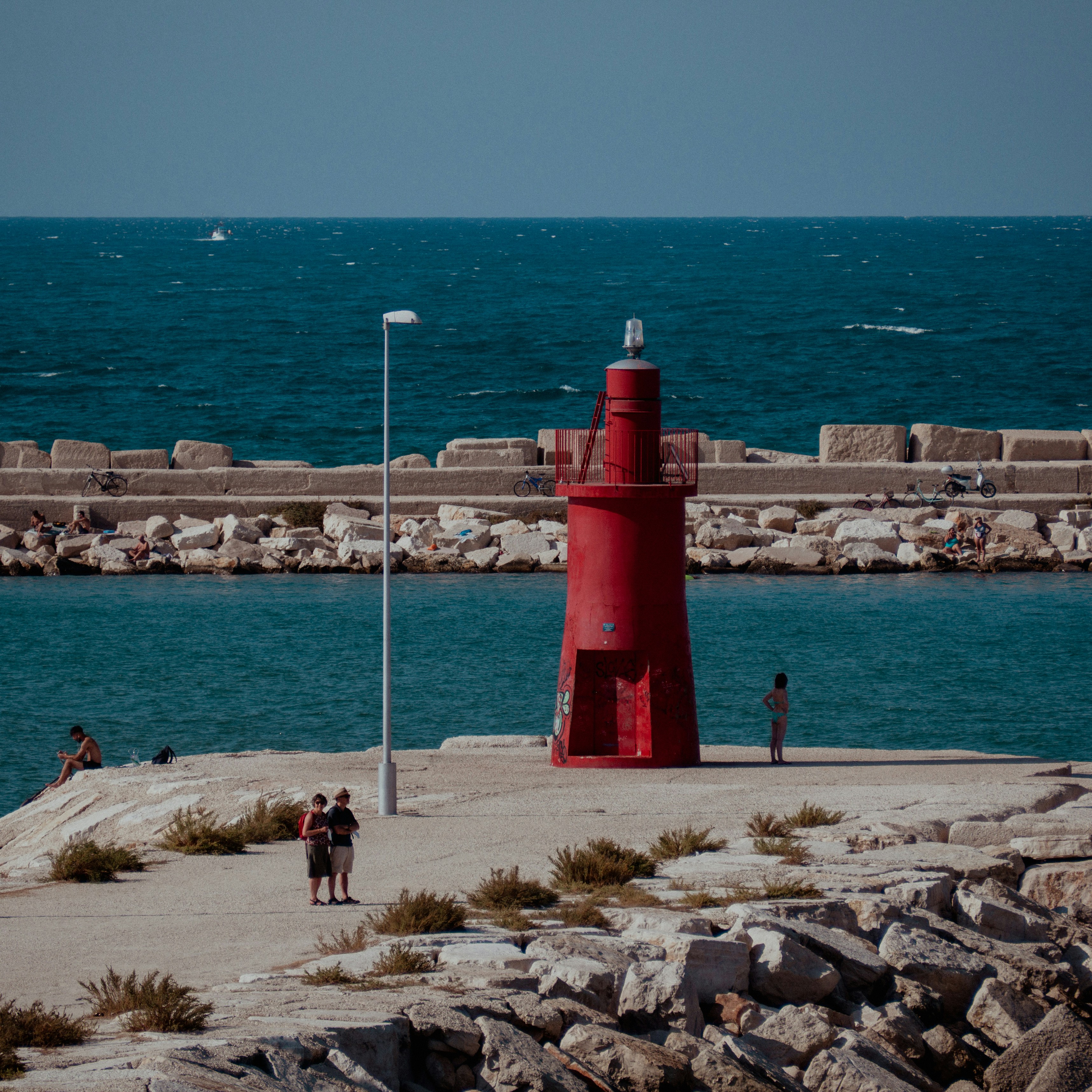 A red lighthouse stands beside the sea.