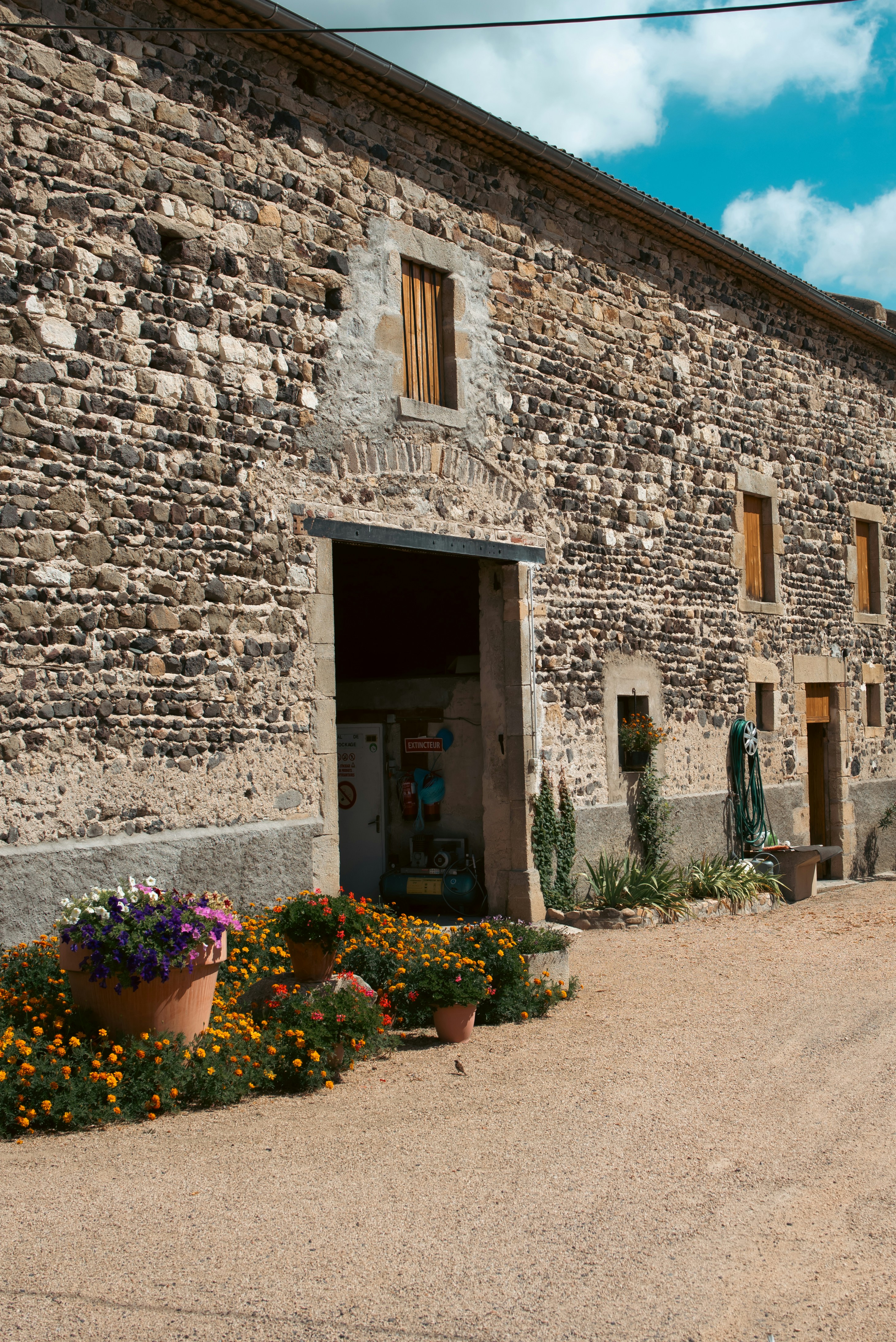 Un edificio in pietra ha fiori e un cielo blu.
