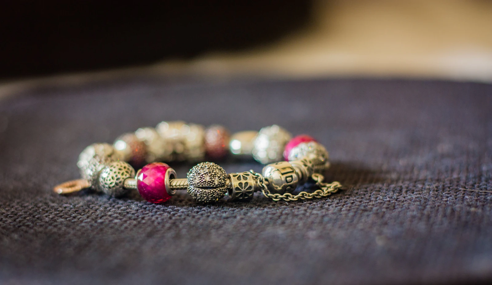 A colorful beaded bracelet on a dark surface. Photo by Jan Kraus on Unsplash.