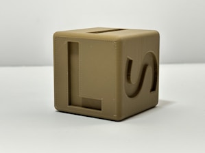 A tan cube toy with letter markings.