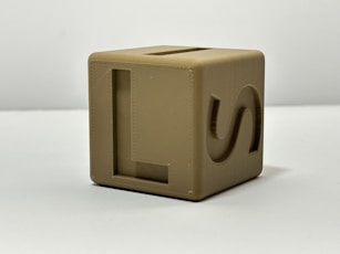 A tan cube toy with letter markings.