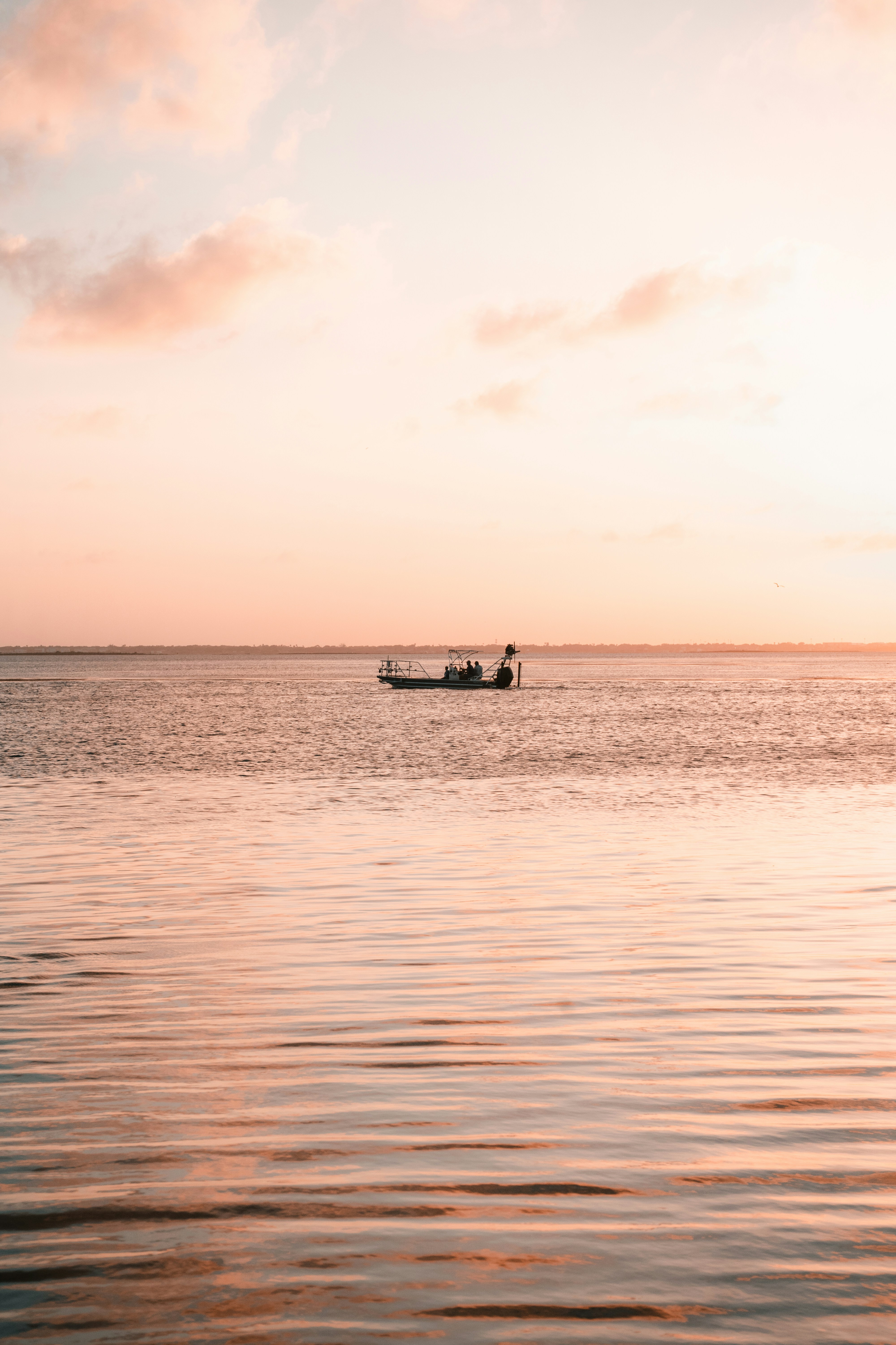 A boat floats on the water at sunset.