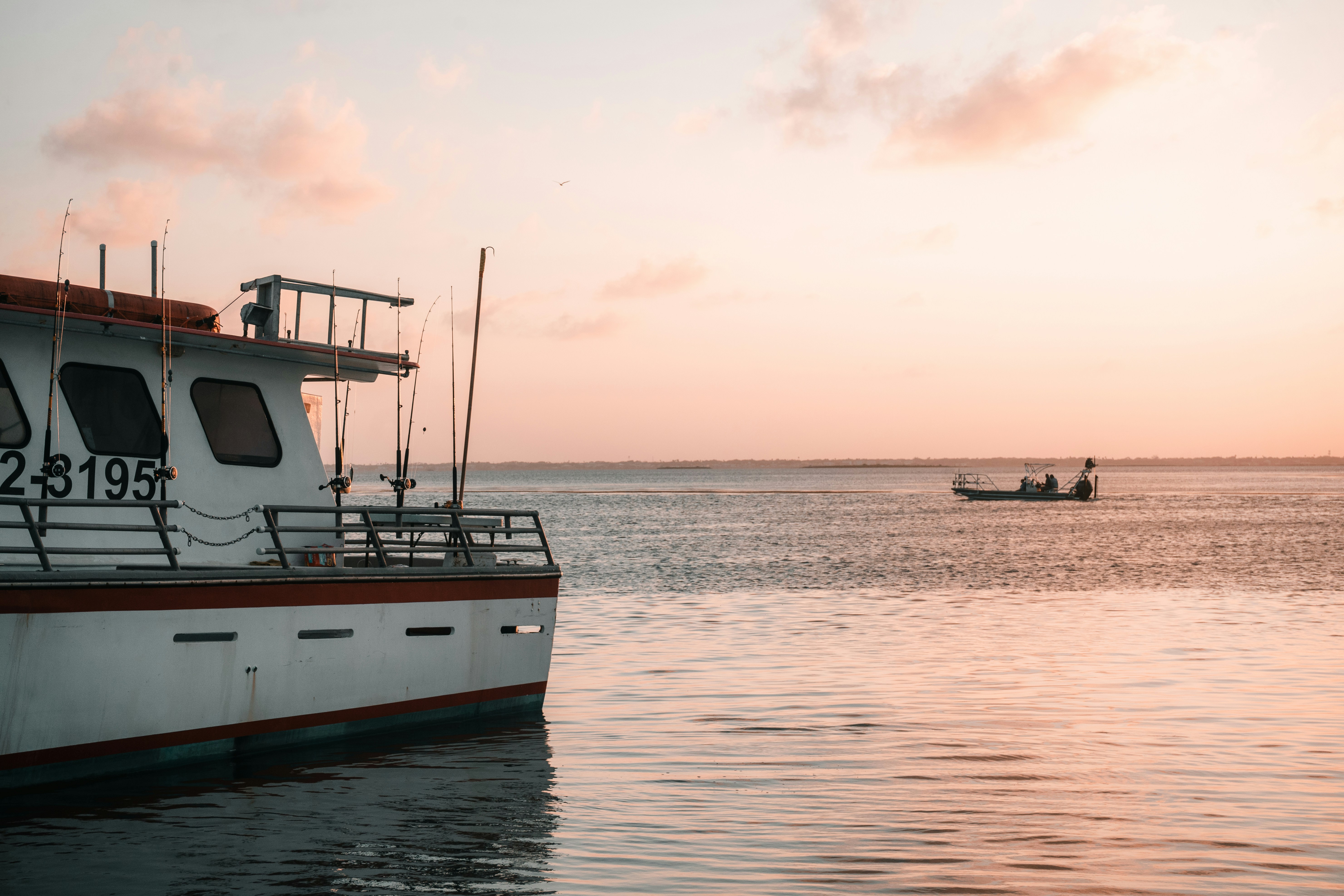Boat floats in calm water at sunset.
