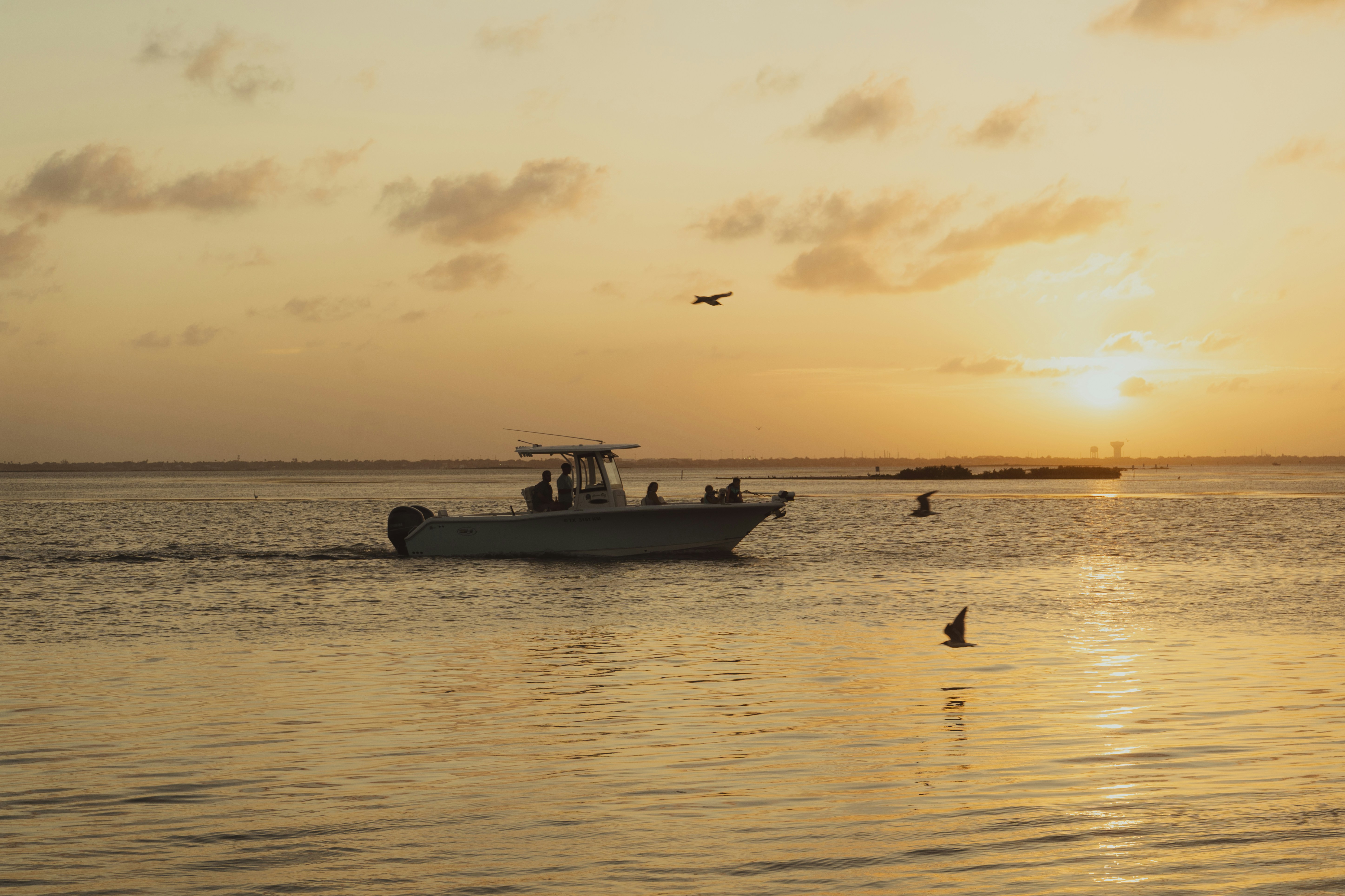 Boat cruises across water during a beautiful sunset.