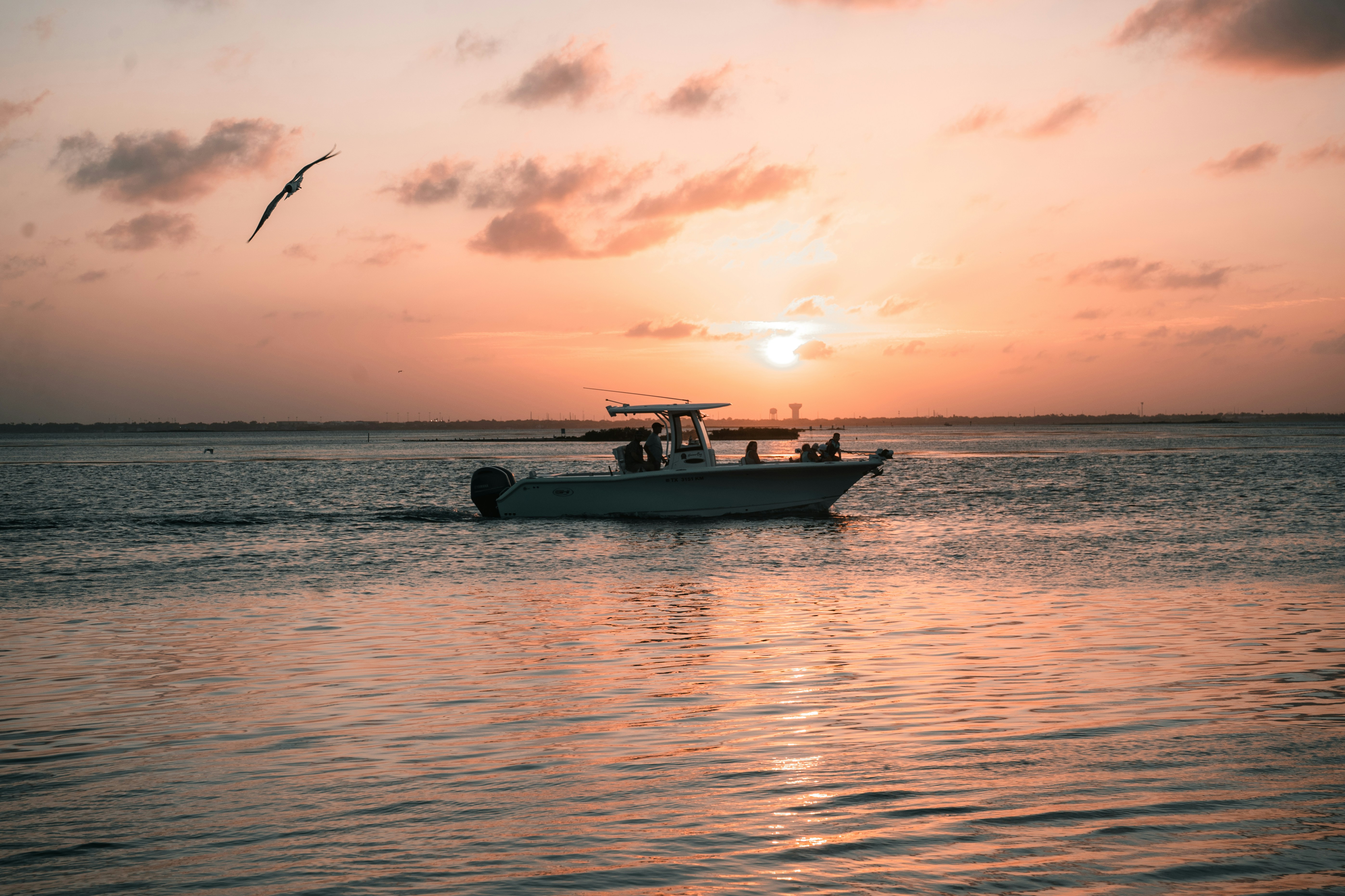 A boat sails across water during a sunset.