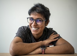 A smiling woman is wearing glasses and a watch.