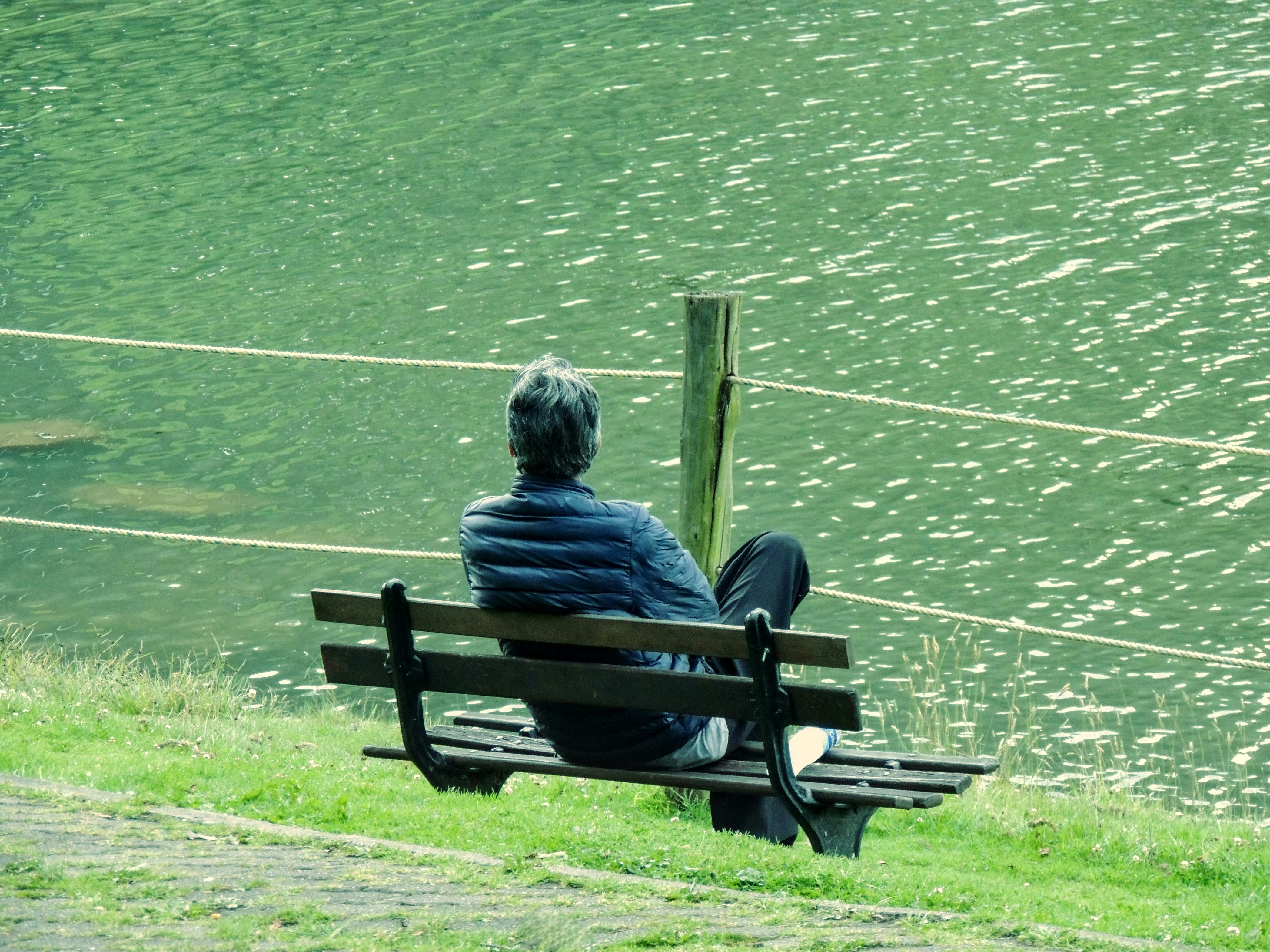 퇴근 후 피로 풀리는 힐링제품 추천 - A person sits on a bench by the water.