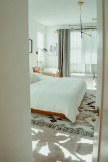 A bright, modern bedroom with a patterned rug.