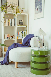 Cozy reading nook with a white chair and green table.
