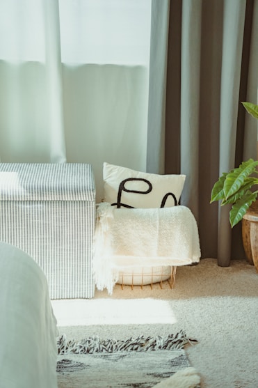 Striped storage ottoman with pillows and blanket.
