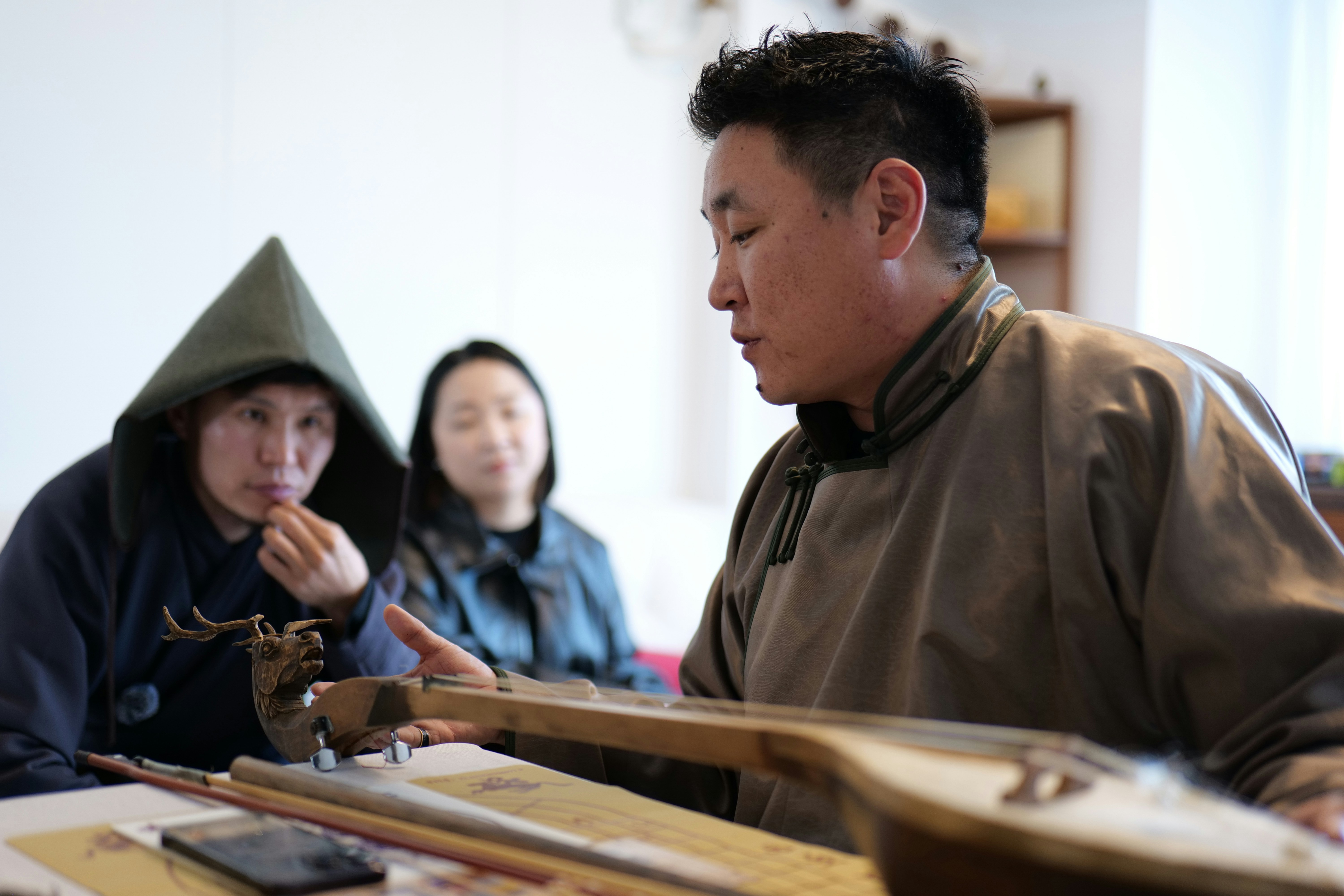 A man demonstrates a traditional instrument to others.