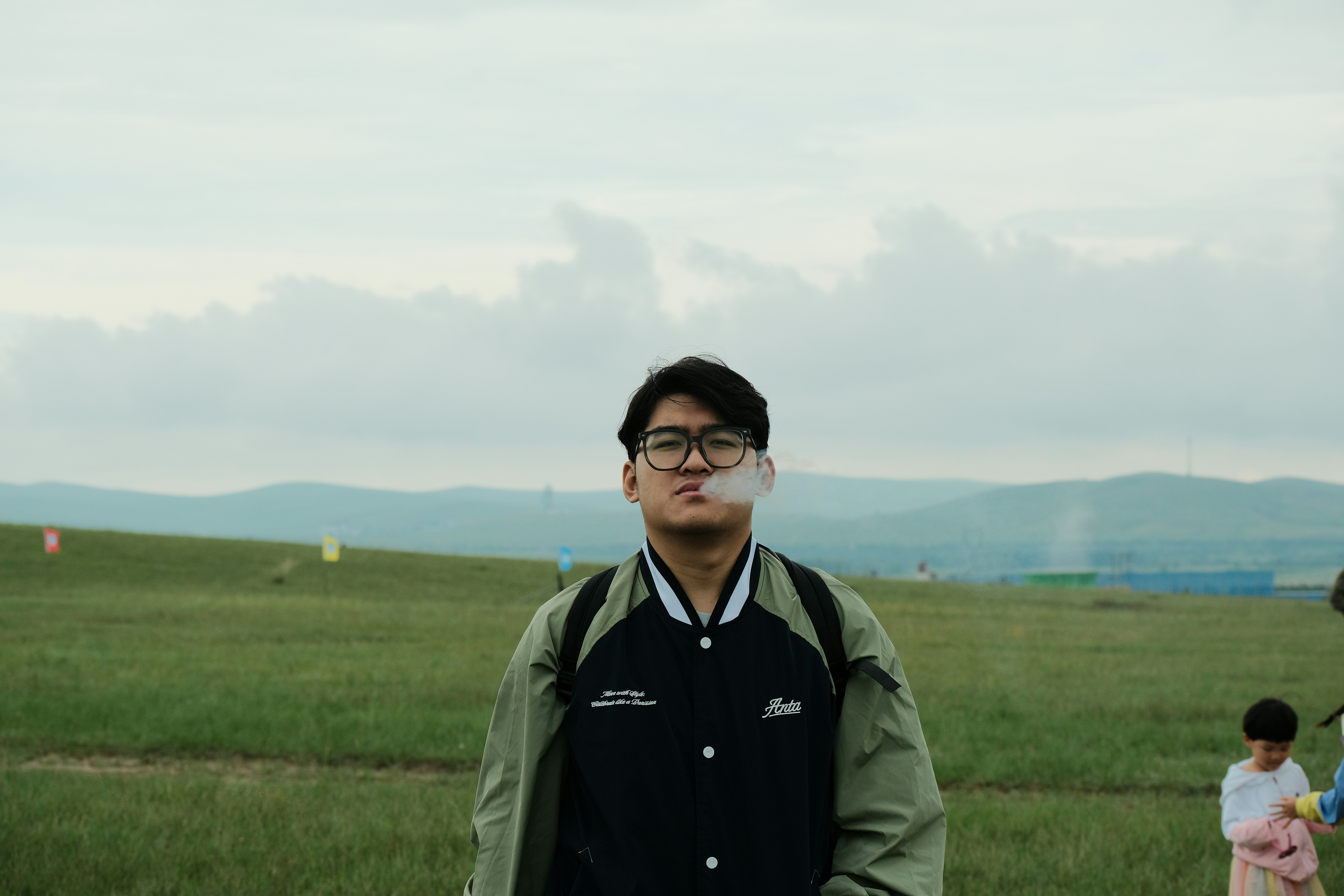 Un hombre fuma al aire libre con un cielo nublado.
