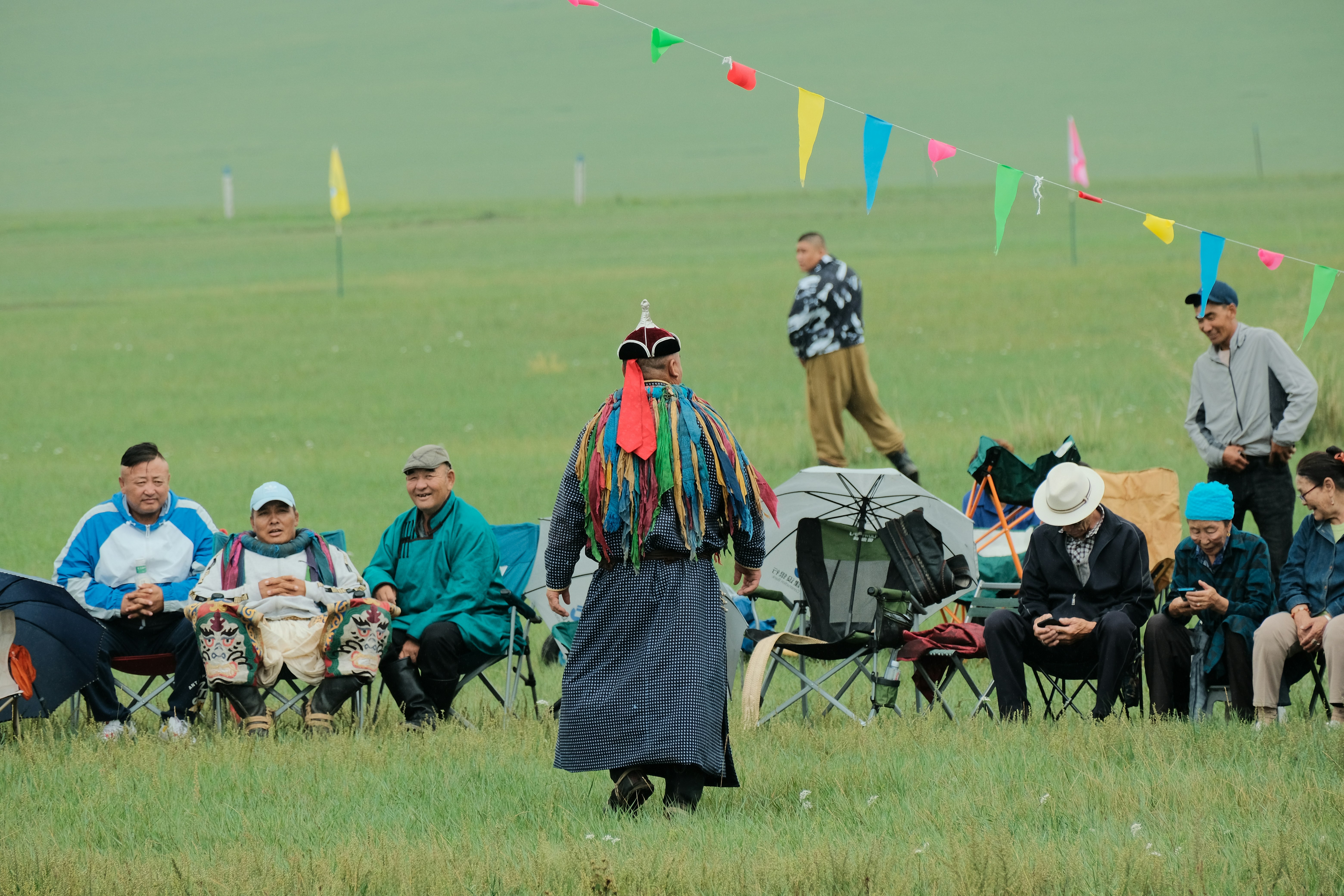 People watch a performance on a grassy field.