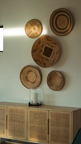 Woven baskets decorate a wall above a wooden sideboard.