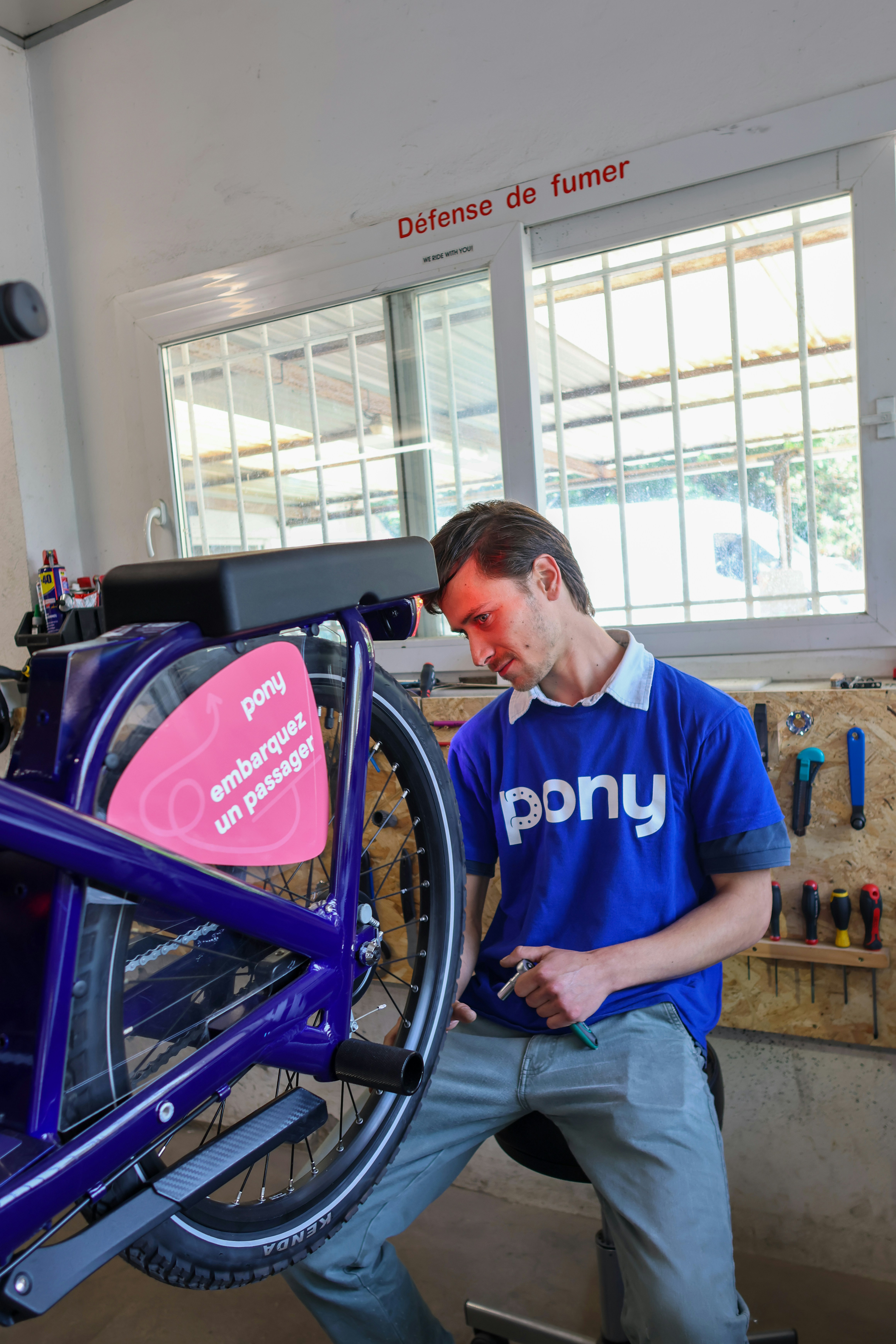 A man repairs a pony bicycle in a workshop.