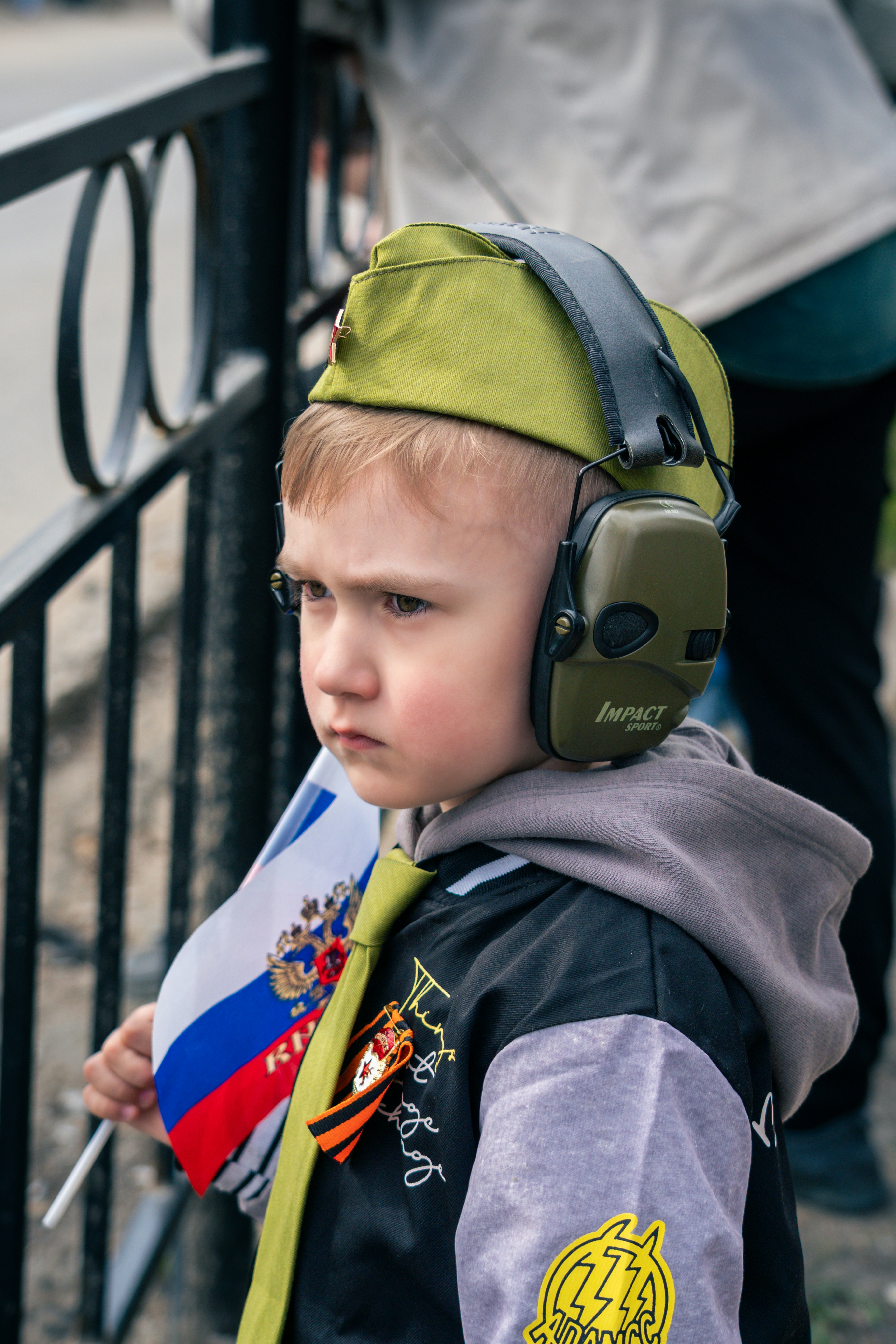 A young boy holds a flag and looks ahead.