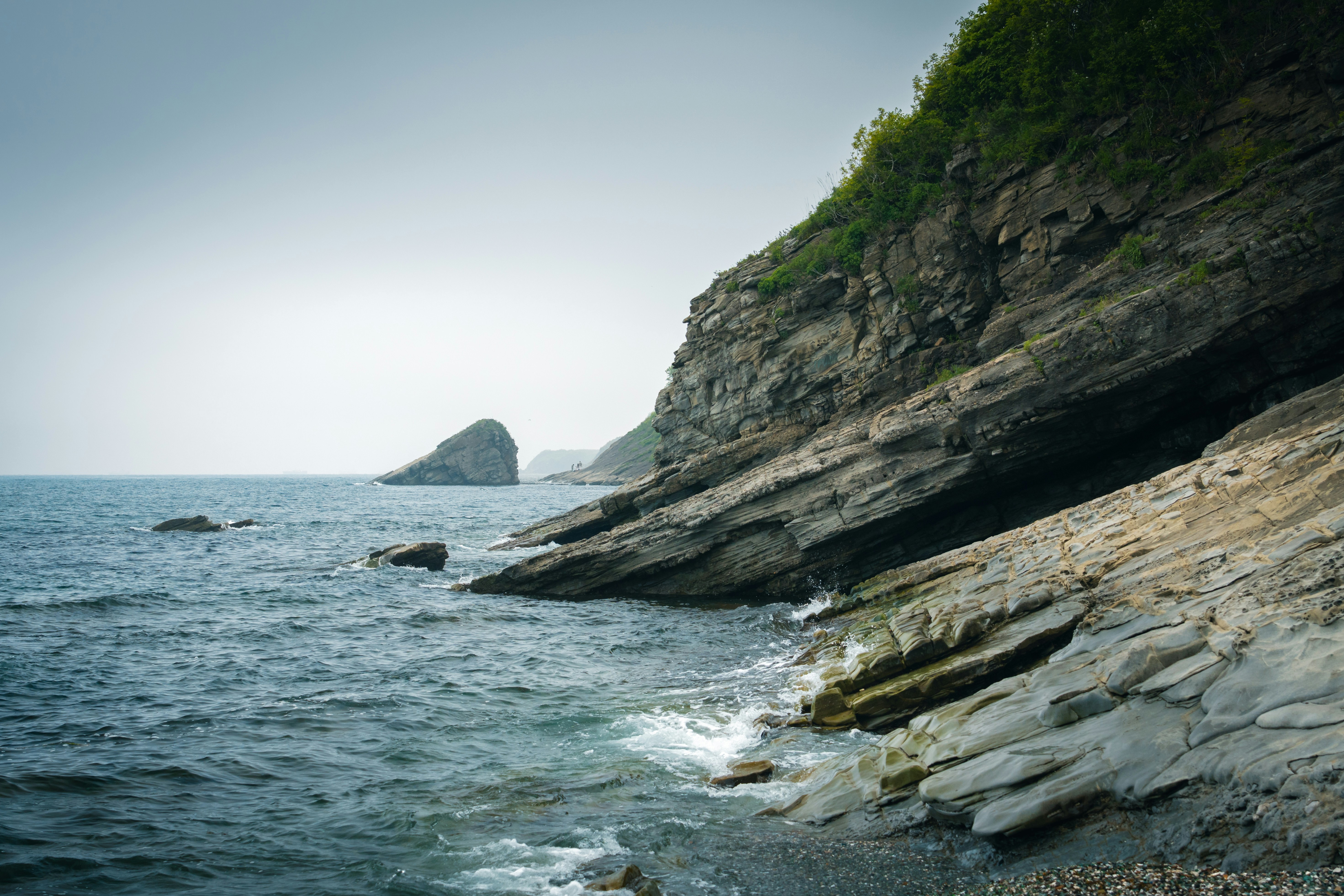 Die felsige Küste überblickt den ruhigen, blauen Ozean.