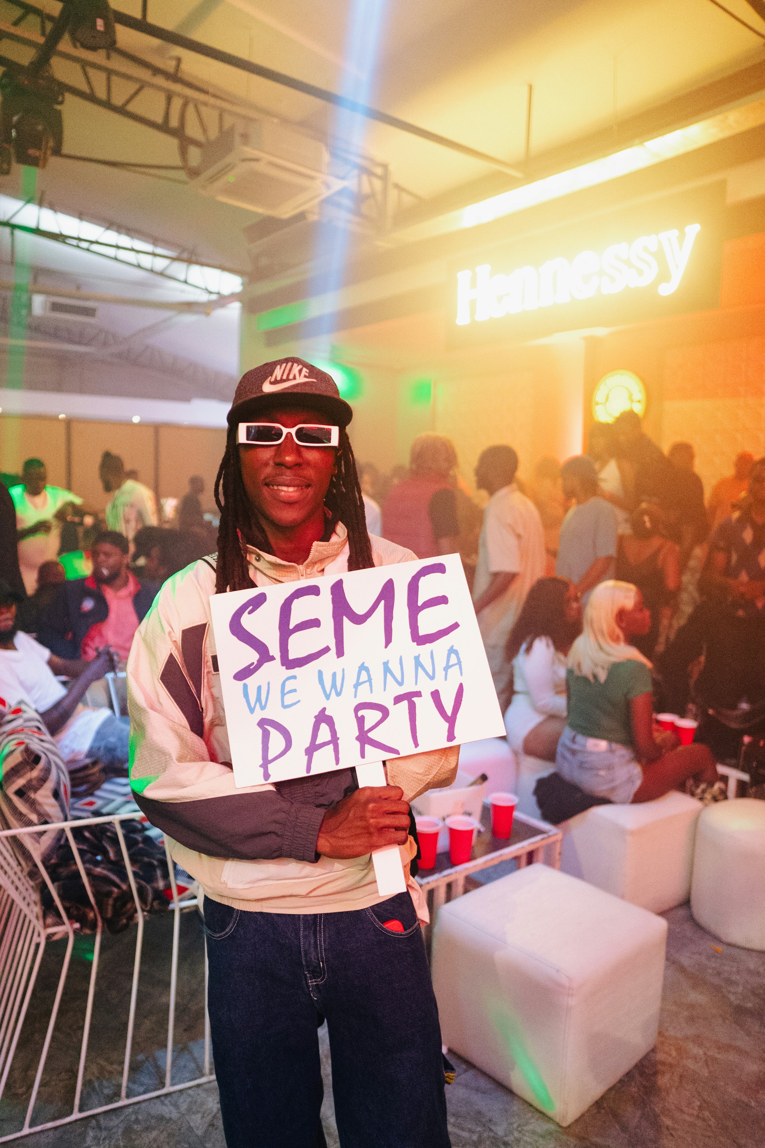 Man holds sign at a hennessy-sponsored party.