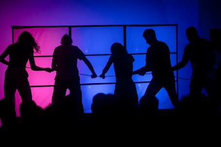 People are pulling on a rope under colorful lights.