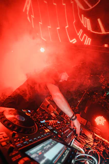 Dj plays music with red lighting and smoke.