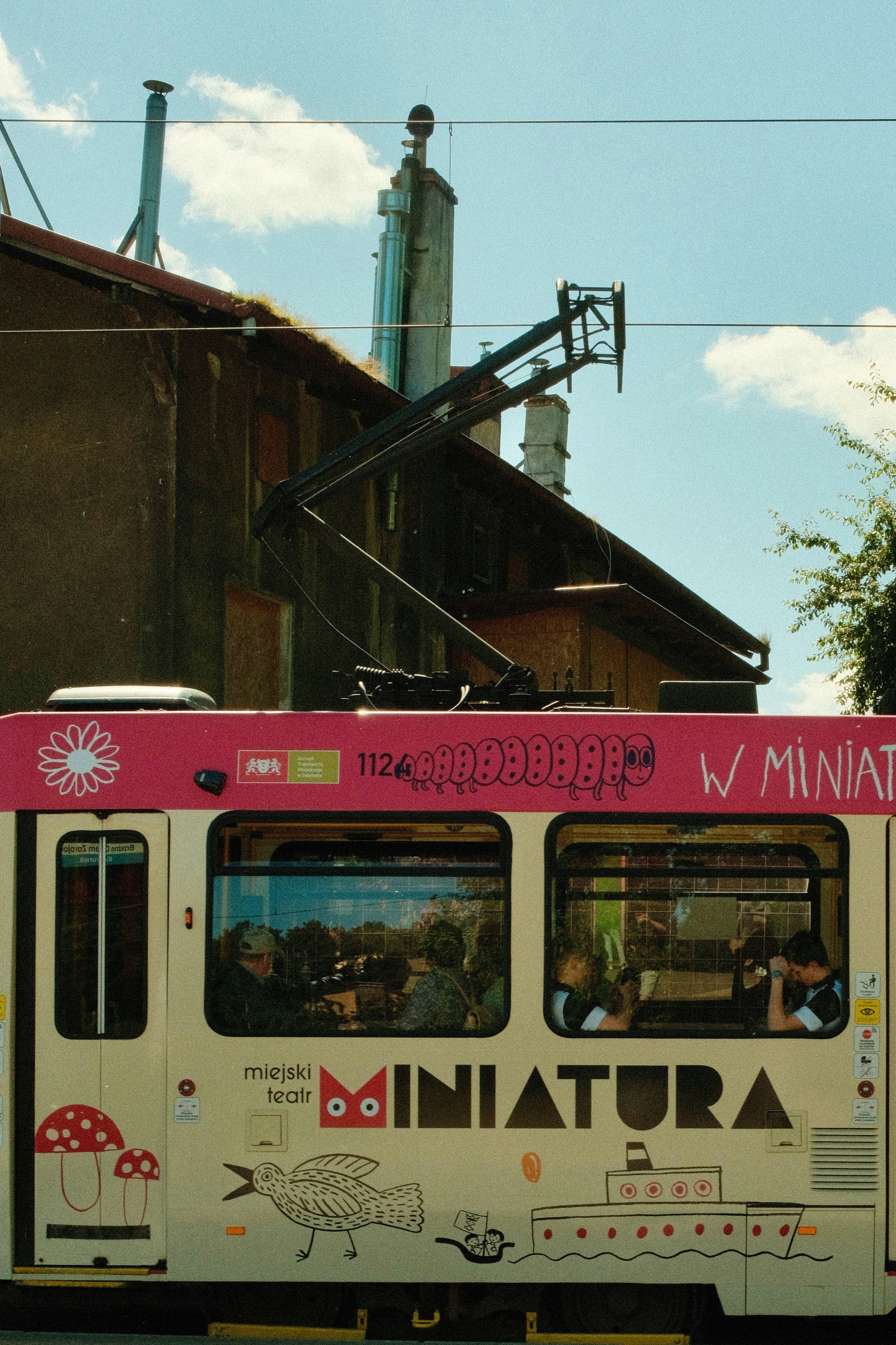 A tram passes by an old building on a sunny day.