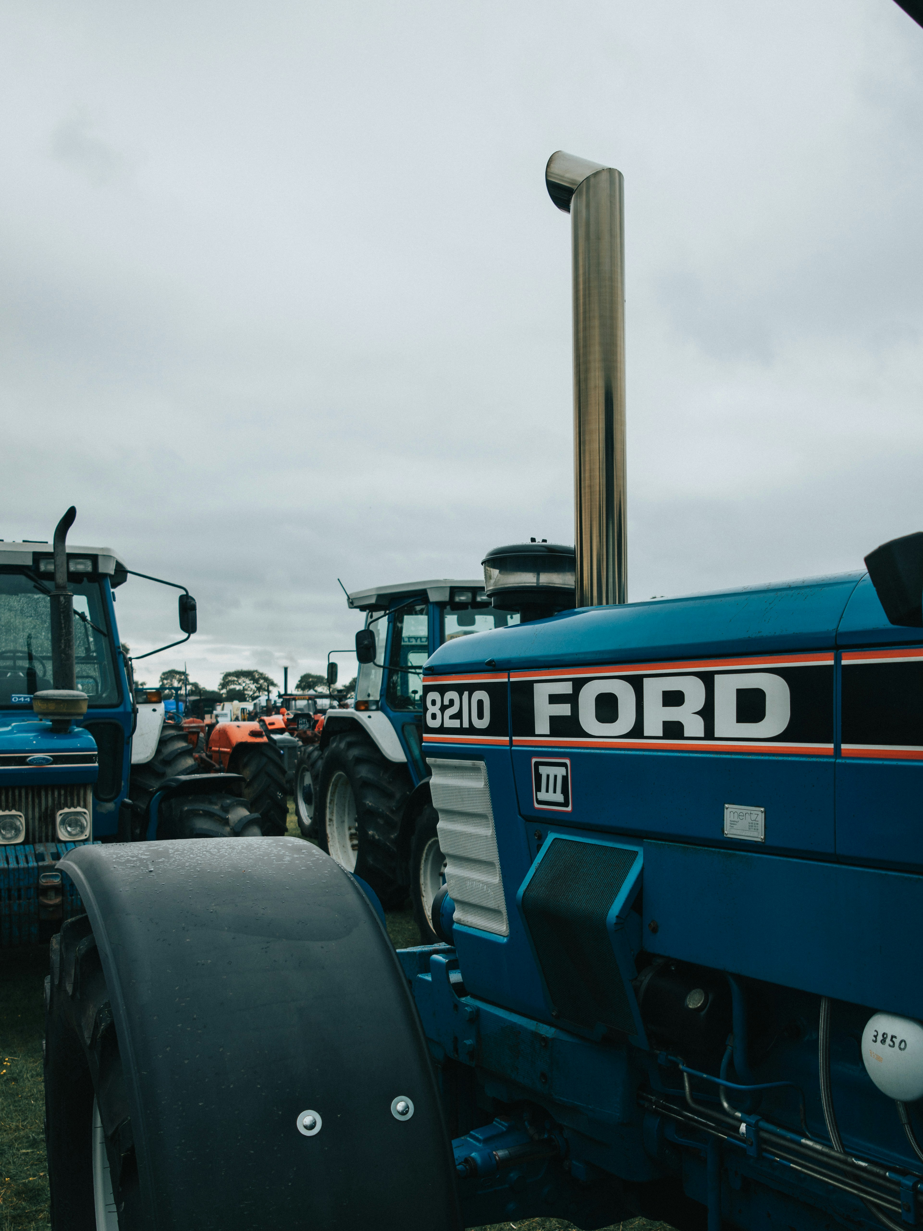 Ford tractors are lined up under a cloudy sky.