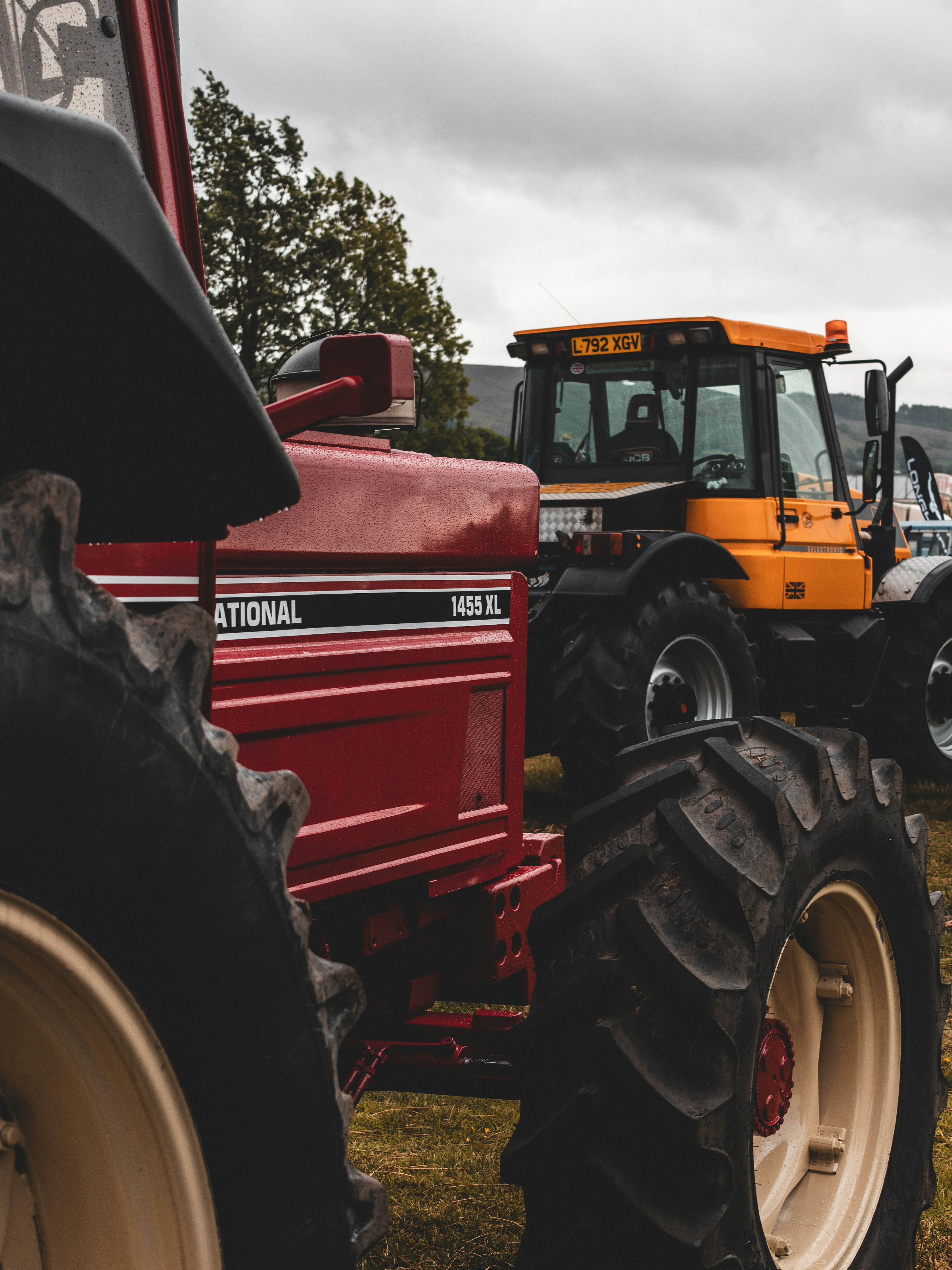 Two tractors are parked outdoors on a cloudy day.