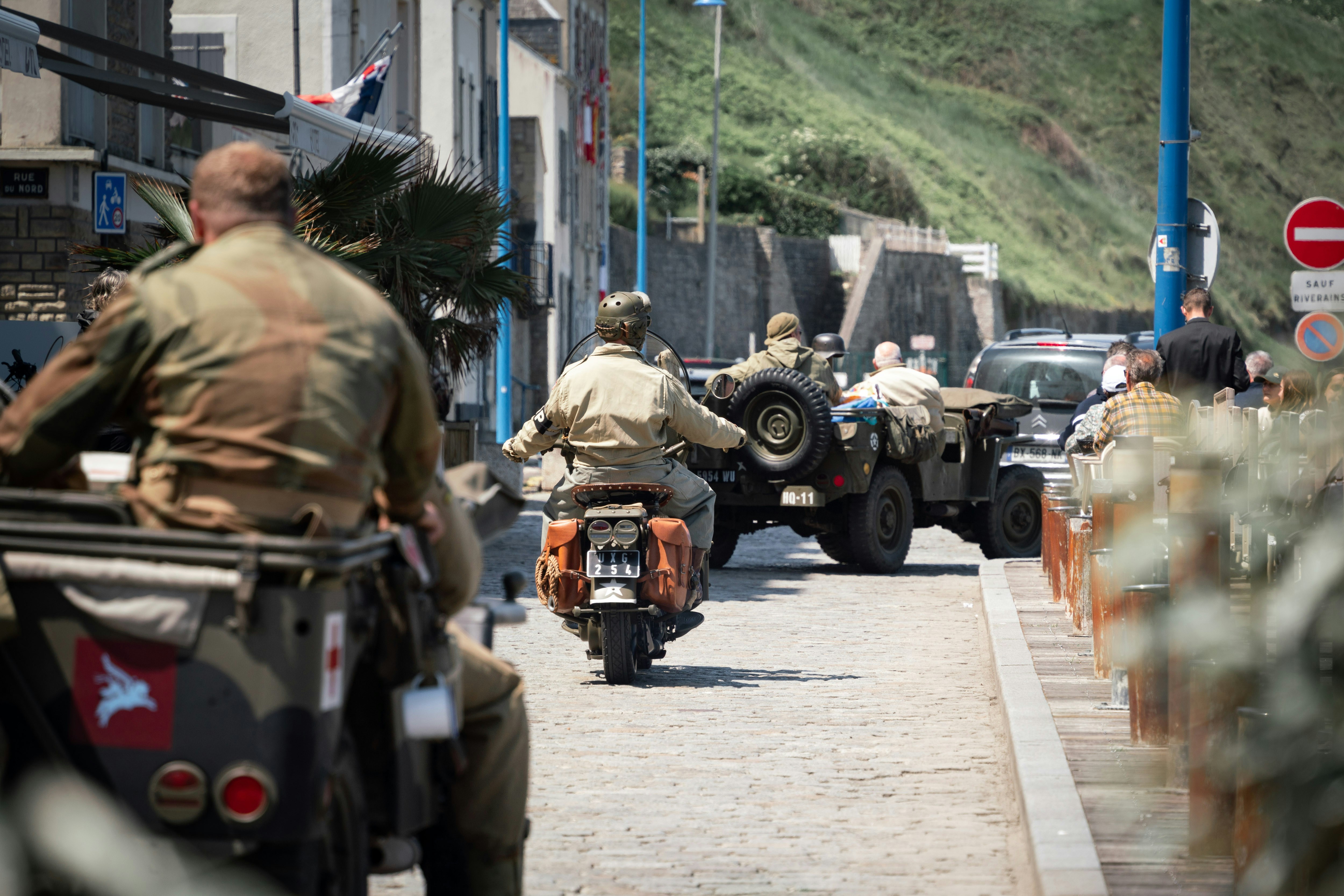 Military vehicles and soldiers drive down the street.